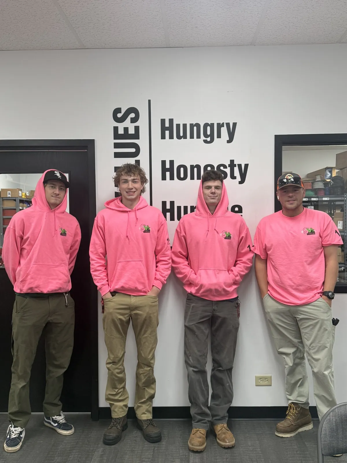 Four GV's technicians in pink Breast Cancer Awareness hoodies.