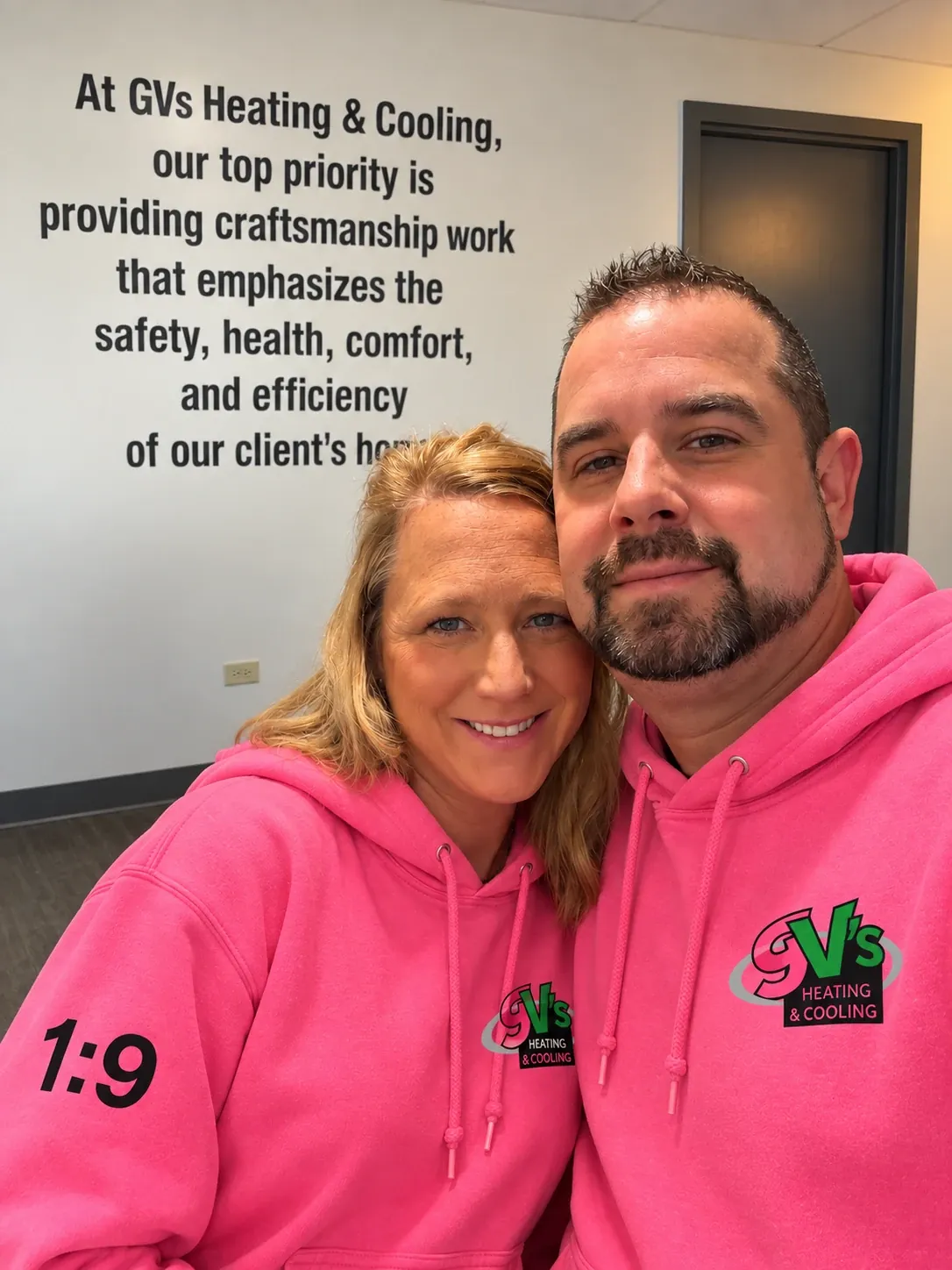 Two of the GV's team in pink hoodies in front of the company mission statement.